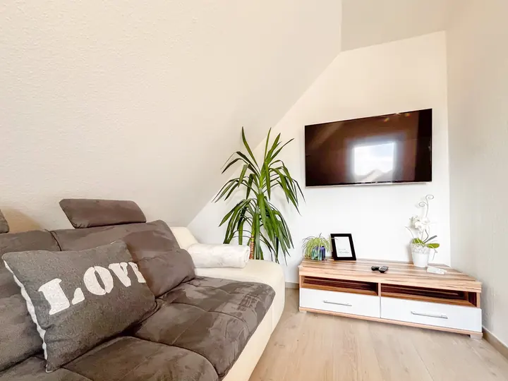 Wohnzimmer mit Fernseher, Sofa und Dekokissen